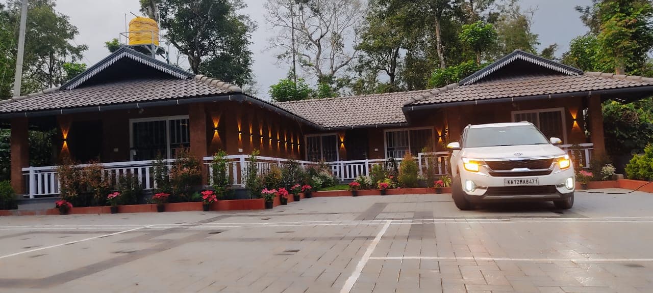 Villa entrance with driveway, parking and flowering plants
